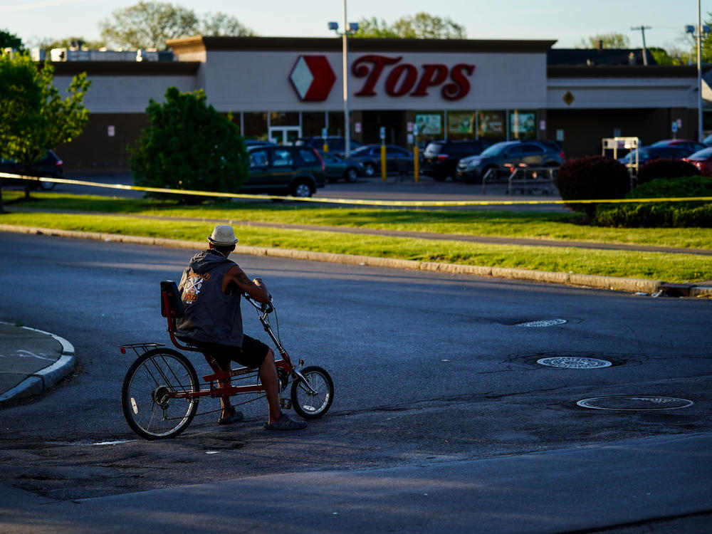 A cyclist pauses outside the site of the supermarket shooting in Buffalo, N.Y. With the Tops store closed for the foreseeable future, the community around it has been left without easy access to healthy and affordable food.