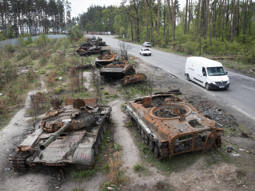 Cars pass destroyed Russian tanks from an earlier battle against Ukrainians in the village of Dmytrivka, close to Kyiv, Ukraine, on Monday. With Russian troops gone from the Kyiv region, life is returning to the city. But heavy fighting takes place daily in the east and the south of the country.