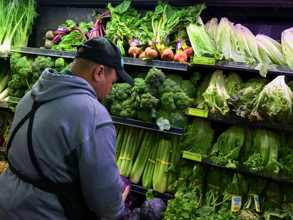 A worker stocks shelves of produce at a supermarket in Washington, D.C., in 2018. Grocery stores provide food access and jobs in a community.