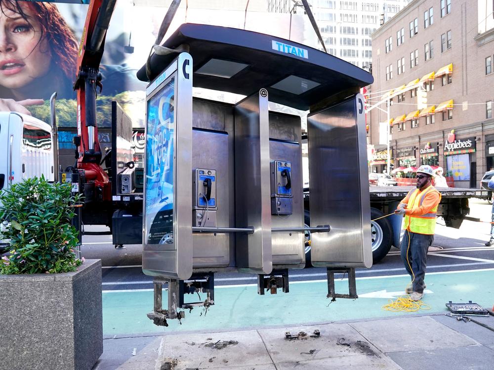 Workers remove the final New York City pay phone near Seventh Avenue and 50th Street in Midtown Manhattan on Monday. Despite the fanfare, there are still some pay phones standing in the city.