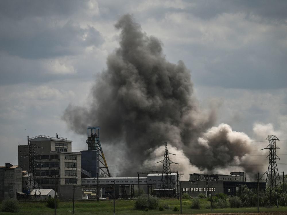 Smoke and debris ascend after a strike at a factory in the city of Soledar, in eastern Ukraine's Donbas region, on Tuesday. At the three-month point since Russia launched its large-scale invasion of Ukraine, fighting has been intensifying in the east.