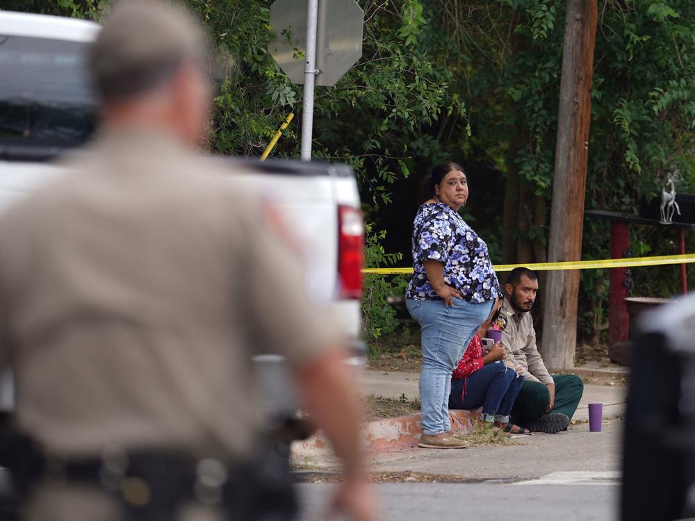 People sit on the curb outside Robb Elementary School in Uvalde, Texas, on May 24.