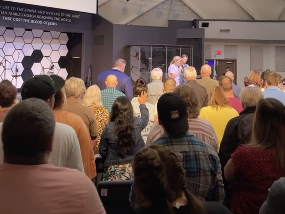 In this screenshot from a Facebook Live video of the church service by Maisey Cook, a woman takes the stage at New Life Christian Church and World Outreach in Warsaw, Ind. with her husband to tell her story of how Pastor John Lowe II had sex with her she was 16 years old.