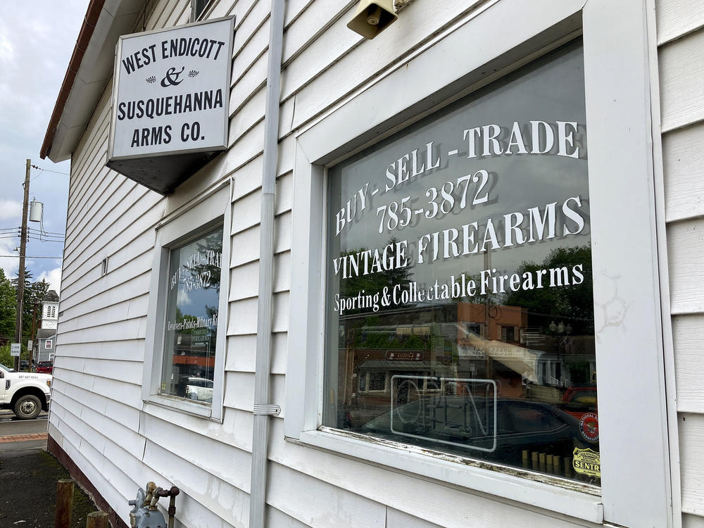 A rifle hangs on display in the window of the West Endicott & Susquehanna Arms Co., where Payton Gendron purchased firearms in Endicott, N.Y.