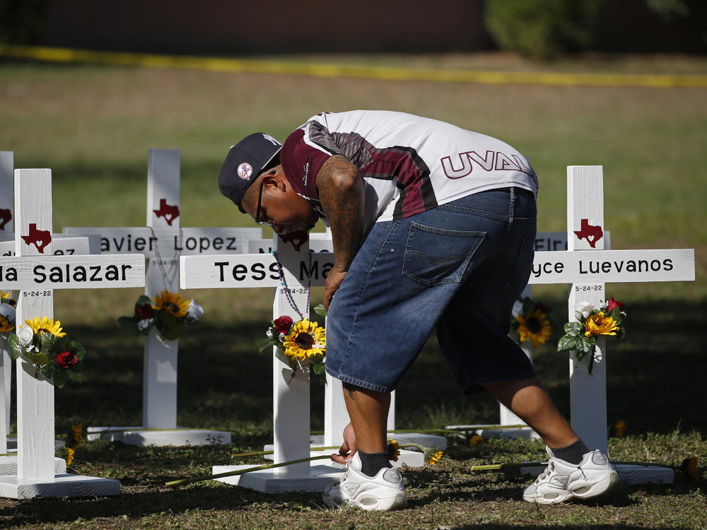 A man places flowers on crosses with the names of children killed outside of Robb Elementary School in Uvalde, Texas, on Thursday.