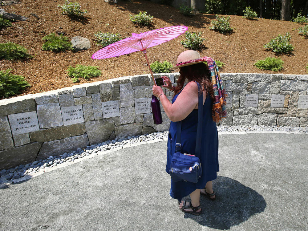 Karla Hailer, a teacher from Scituate, Mass., takes a video on July 19, 2017, where a memorial stands at the site in Salem, Mass., where five women were hanged as witches more than three centuries years earlier. Massachusetts lawmakers on have formally exonerated Elizabeth Johnson Jr., clearing her name 329 years after she was convicted of witchcraft at the height of the Salem Witch Trials.