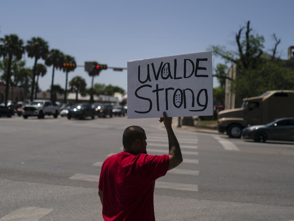 Alex Covarrubias, 32, on Thursday holds up a sign at a street corner for the victims of Tuesday's shooting at Robb Elementary School.