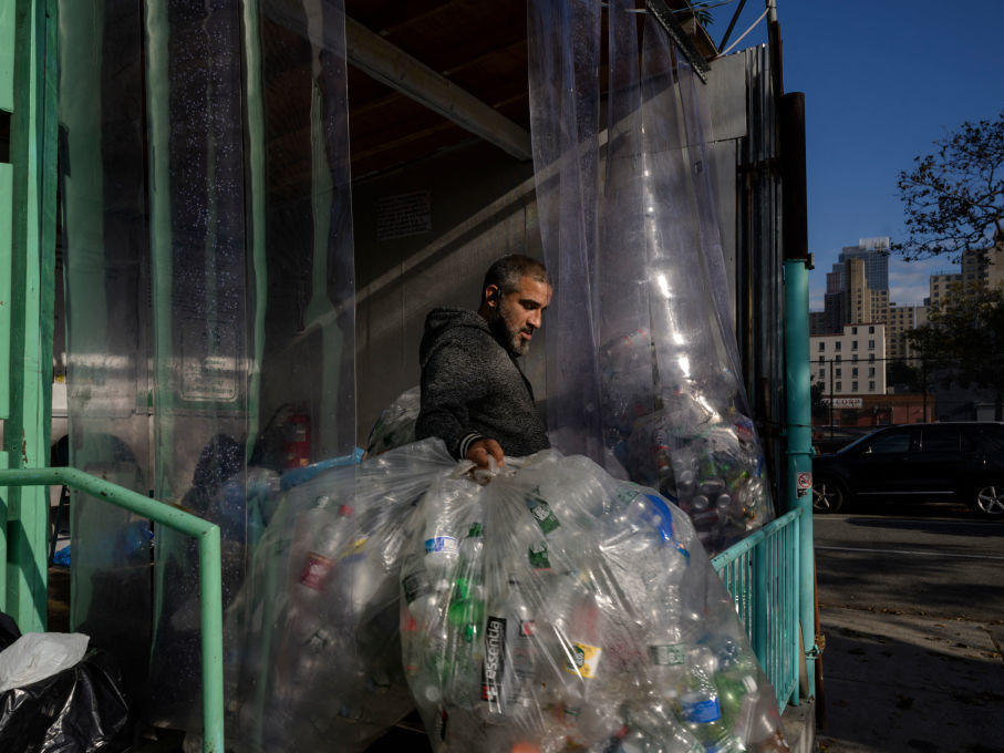 A worker carries used drink bottles and cans for recycling at a collection point in Brooklyn, New York. Three decades of recycling have so far failed to reduce what we throw away, especially plastics.