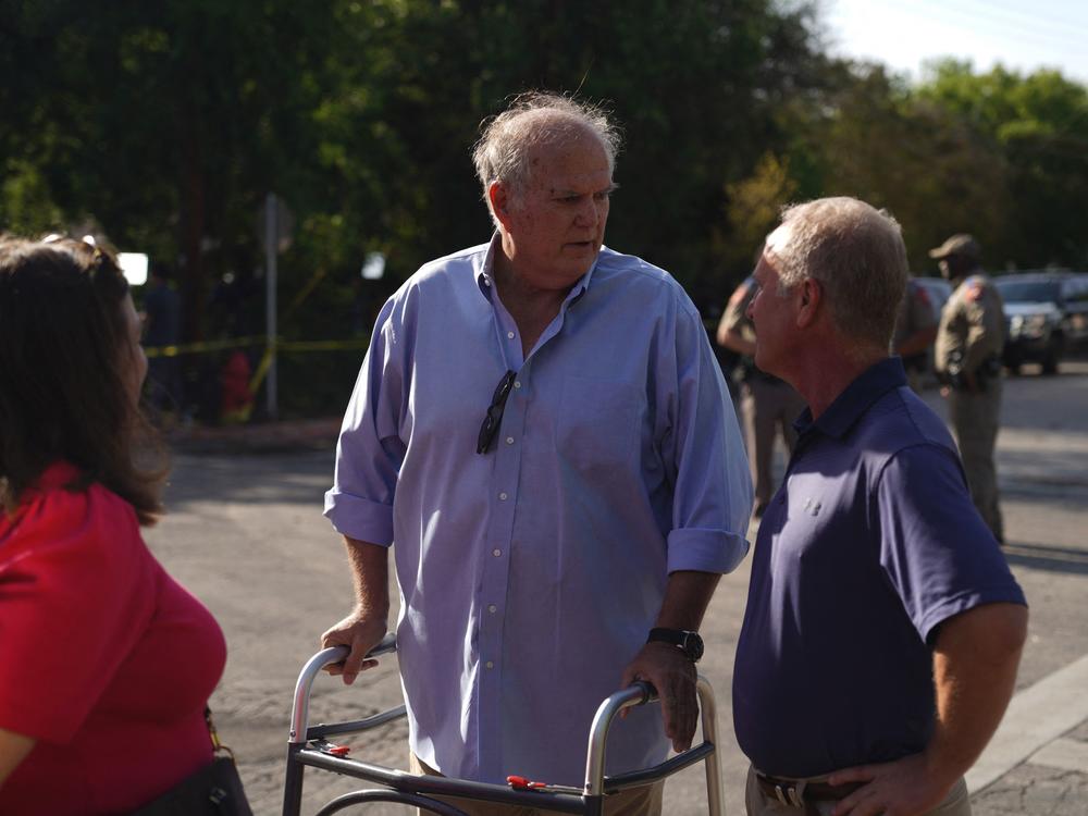 Don McLaughlin (center), the mayor of Uvalde, Texas, leaves Robb Elementary School after a visit on Wednesday, the day after a gunman killed 19 children and two adults at the school.
