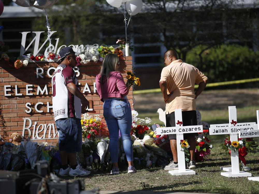 People pay their respects on Thursday at a memorial set up outside Robb Elementary School in Uvalde, Texas, the scene of the United States' most recent mass shooting. The killing of 19 children and two adults has reignited heated debates over gun control.