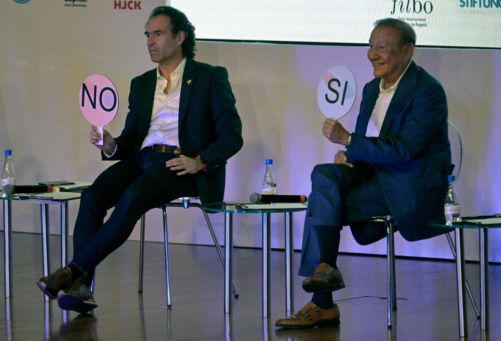 Colombian presidential candidates Federico Gutiérrez (left) and Rodolfo Hernández hold up signs during a debate in Bogotá on April 20.