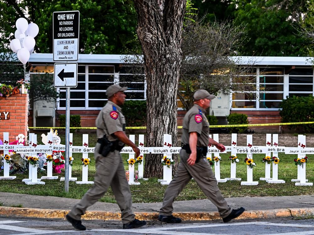 Police officers walk past a makeshift memorial for the shooting victims at Robb Elementary School in Uvalde, Texas, on Thursday.