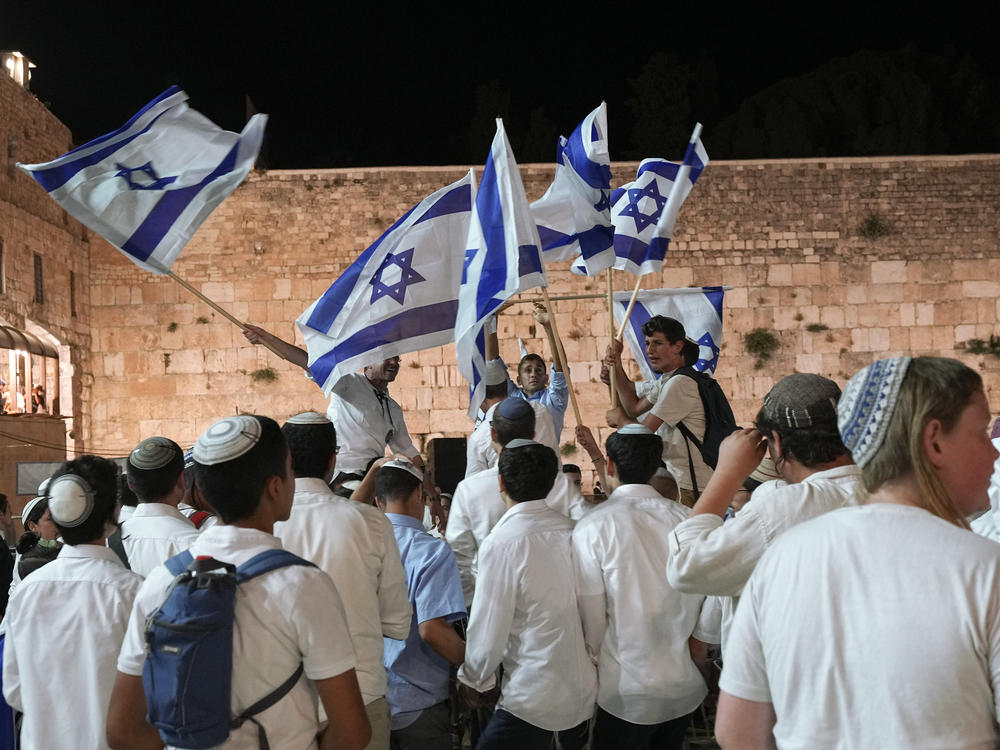 Members of Jewish youth movements dance and wave Israeli flags on the eve of Jerusalem Day an Israeli holiday celebrating the capture of the Old City during the 1967 Mideast war, next to the Western Wall, the holiest site where Jews can pray, in the Old City of Jerusalem, Saturday, May 28, 2022.