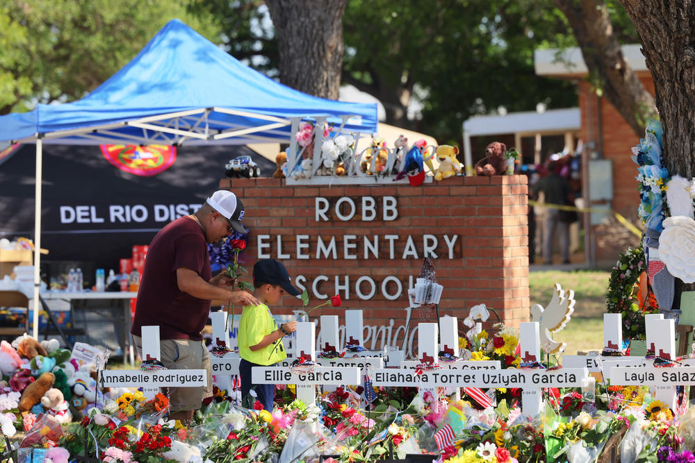 A man and a child pay their respects at a memorial to the victims of the Robb Elementary School mass shooting on Saturday in Uvalde, Texas.