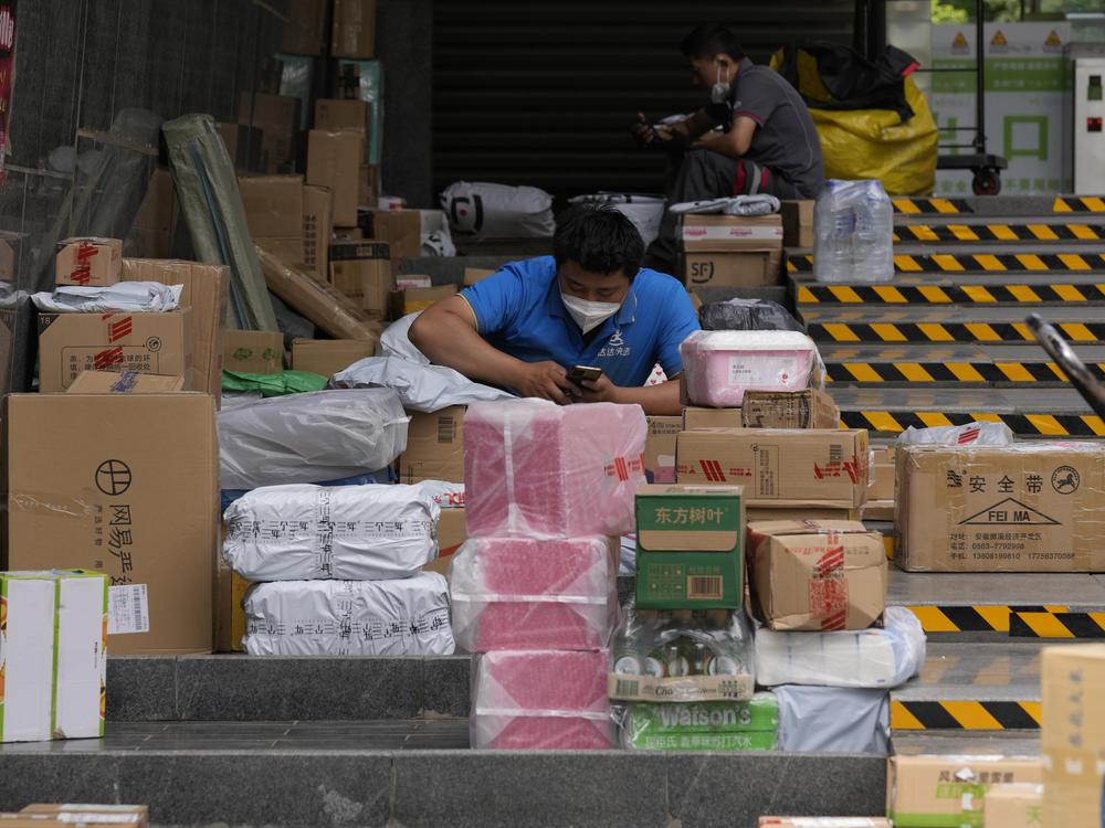 Delivery men sort out their parcels outside a community on Tuesday, May 31, 2022, in Beijing.