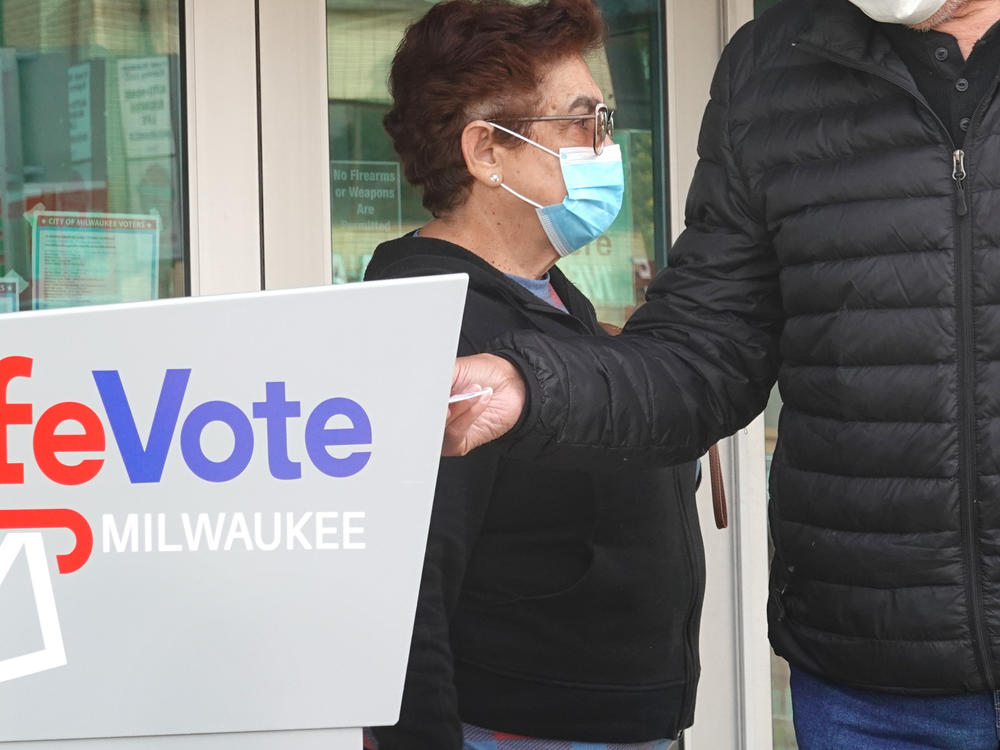 Residents drop mail-in ballots in an official ballot box outside of a Milwaukee library on Oct. 20, 2020.
