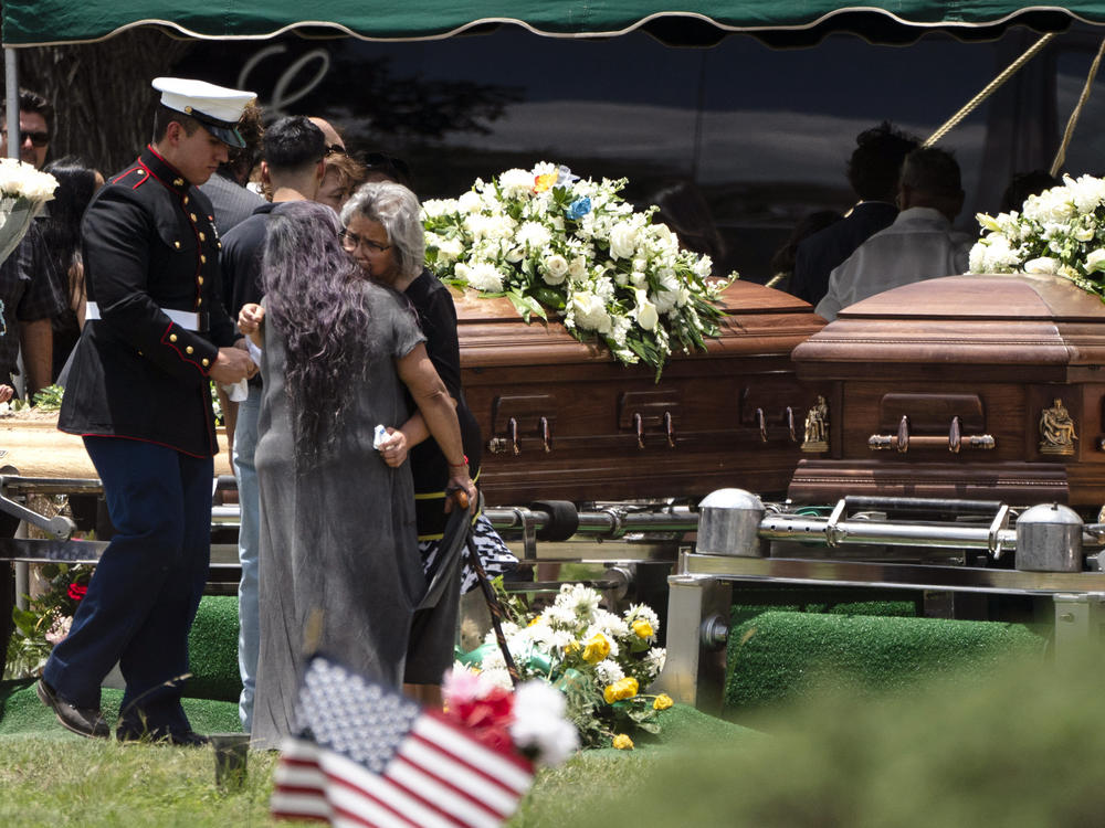 Mourners comfort each other Wednesday during the burial service for Irma Garcia and her husband Joe Garcia at Hillcrest Cemetery in Uvalde, Texas. Irma Garcia was killed in last week's elementary school shooting. Joe Garcia died two days later.