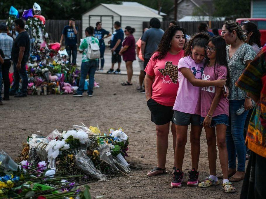 People mourn Tuesday at a makeshift memorial for the victims of the Robb Elementary School shooting in Uvalde, Texas. The Texas town of Uvalde began on Tuesday laying to rest the 19 young children killed in an elementary school shooting that left the small, tight-knit community united in grief and anger.