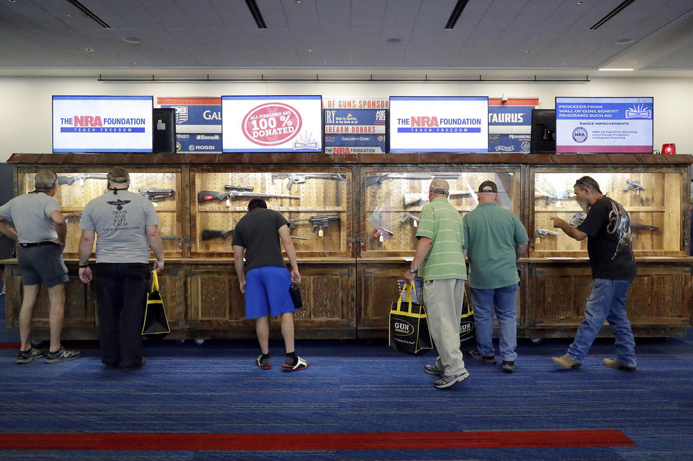 Convention attendees look at various rifles and handguns in display cases that will be raffled off at the Gallery of Guns booth at the NRA annual meeting held in Houston on May 26.