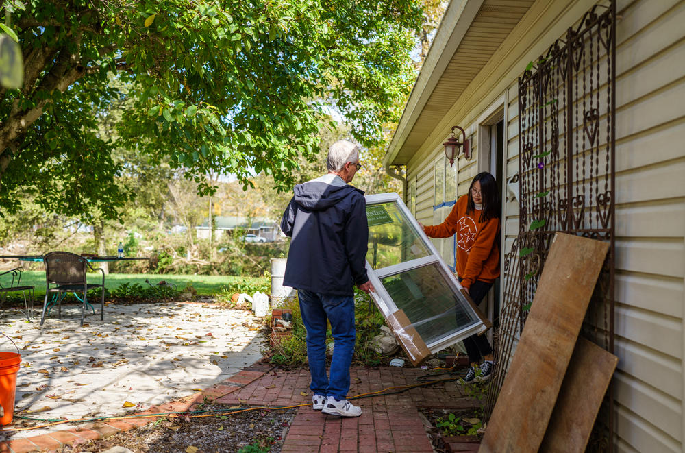 Zoe and her father Danny Turner carry a new window into their home, where they are storing materials to rebuild the property.