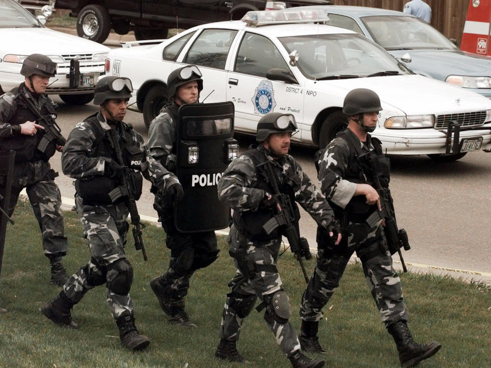 Members of a police SWAT team march to Columbine High School in Littleton, Colorado, as they prepare to do a final search of the campus after two students opened fire there in a mass shooting on April 20, 1999.