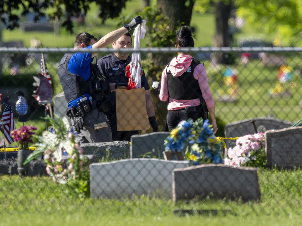 Law enforcement examine a bloody garment while working at the scene of a shooting on Thursday at Graceland Cemetery in Racine, Wis.