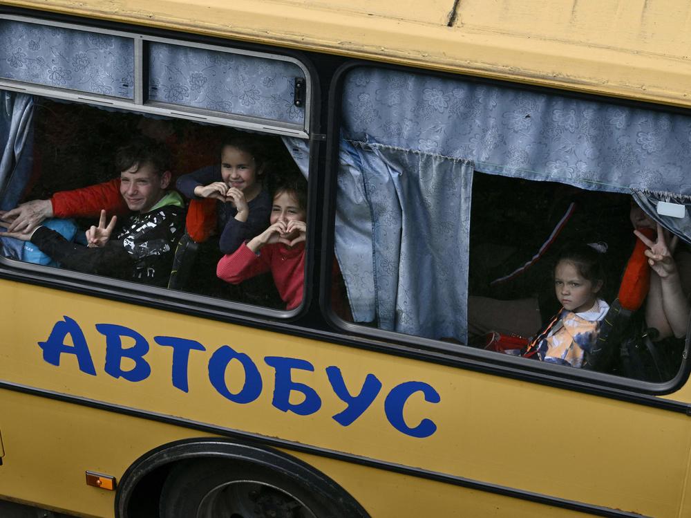 Young Ukrainian evacuees react in a bus while they drive on a road east of Kharkiv, in northeastern Ukraine, on May 30, during the Russian invasion of Ukraine.