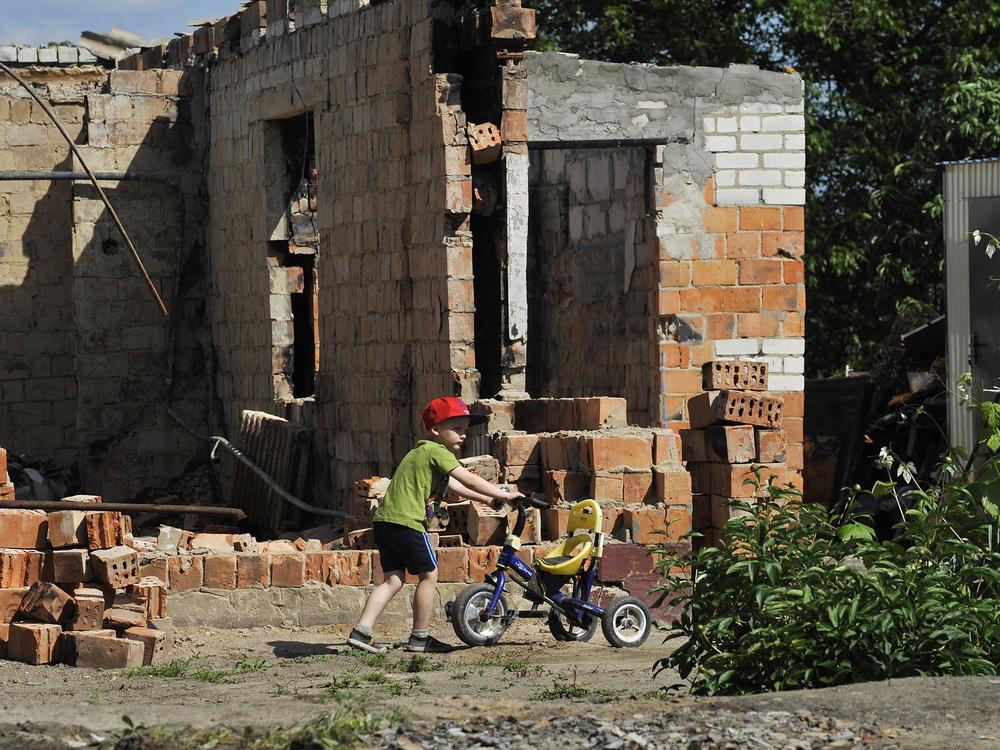 A boy plays in front of a destroyed house in the village of Andriivka, Kyiv region, on Friday, the 100th day of the Russian invasion of Ukraine.
