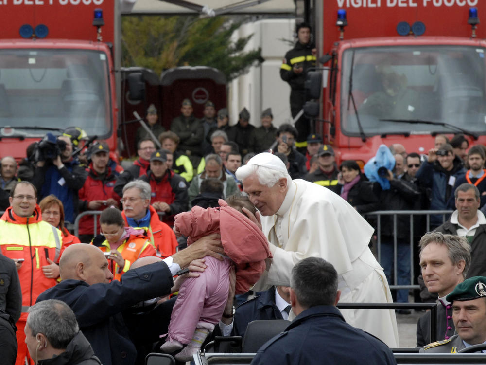 Pope Benedict XVI kisses a baby being held up to him, in Coppito, near L'Aquila, Italy, in 2009. Four years later, the 85-year-old Benedict announced he no longer had the strength of body and mind to carry on the rigors of the papacy.