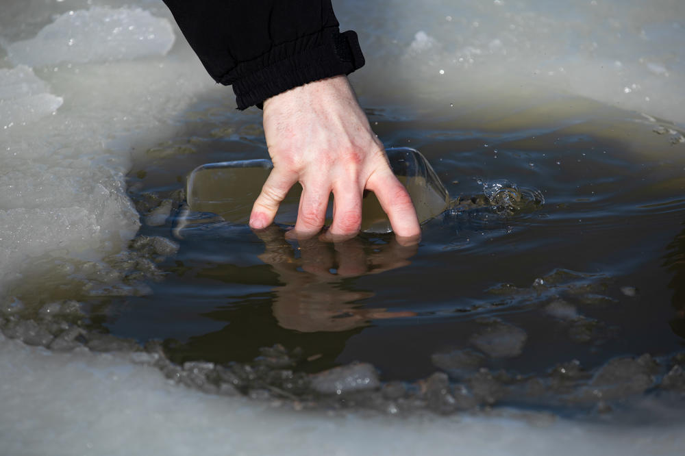 Ryan Wagner fills a glass bottle with water from Lake Erie's Sandusky Bay on Feb. 9 to take back to the lab for analysis.