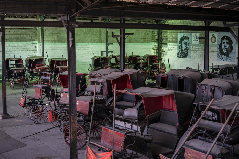 Horse carts used to give rides to tourists sit idle in the garage of a cooperative where murals of the late leader Fidel Castro and revolutionary hero Ernesto 