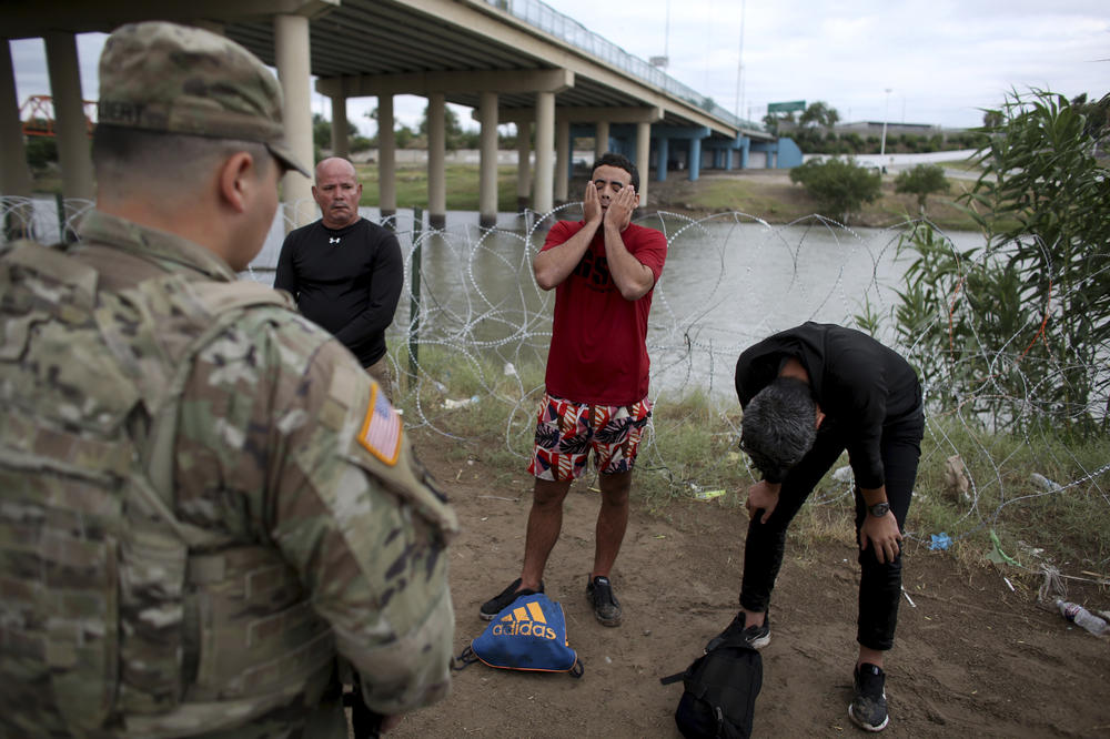 Three migrants from Cuba stand in front of a U.S. National Guardsman after crossing the Rio Grande river in Eagle Pass, Texas, on May 22. U.S. officials have recorded far higher numbers of Cuban nationals at the border than last year.