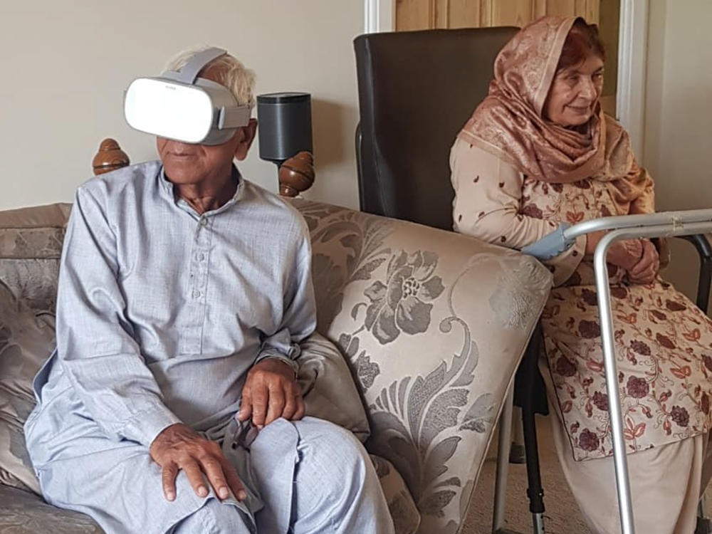 In London, Partition survivor Bahadur Ali Phambra (left) watches a video through a virtual reality headset provided by Project Dastaan. His wife Janat Bibi is on the right.