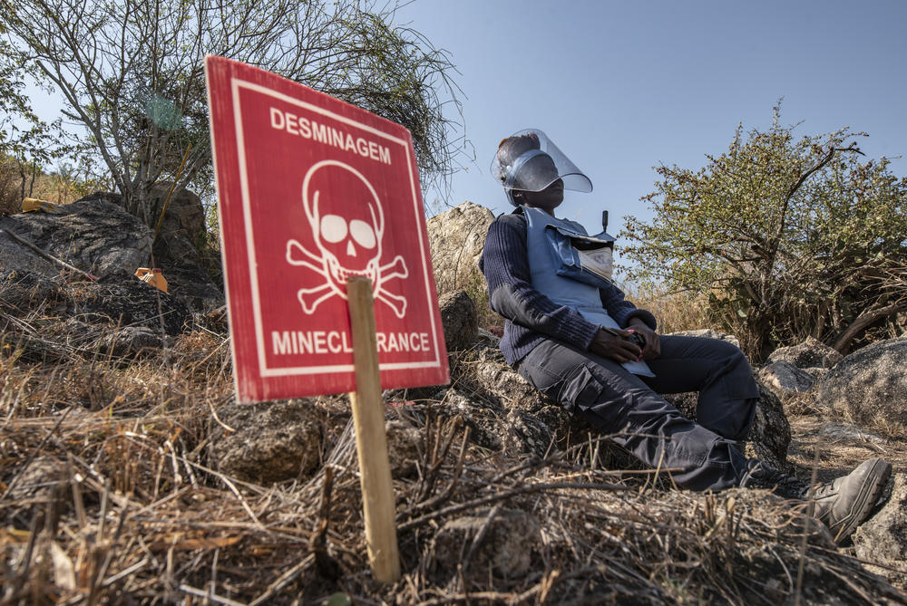 Esperanca Ngando, a mine clearance supervisor, takes a break near a sign that marks the location of a newly discovered anti-personnel mine.