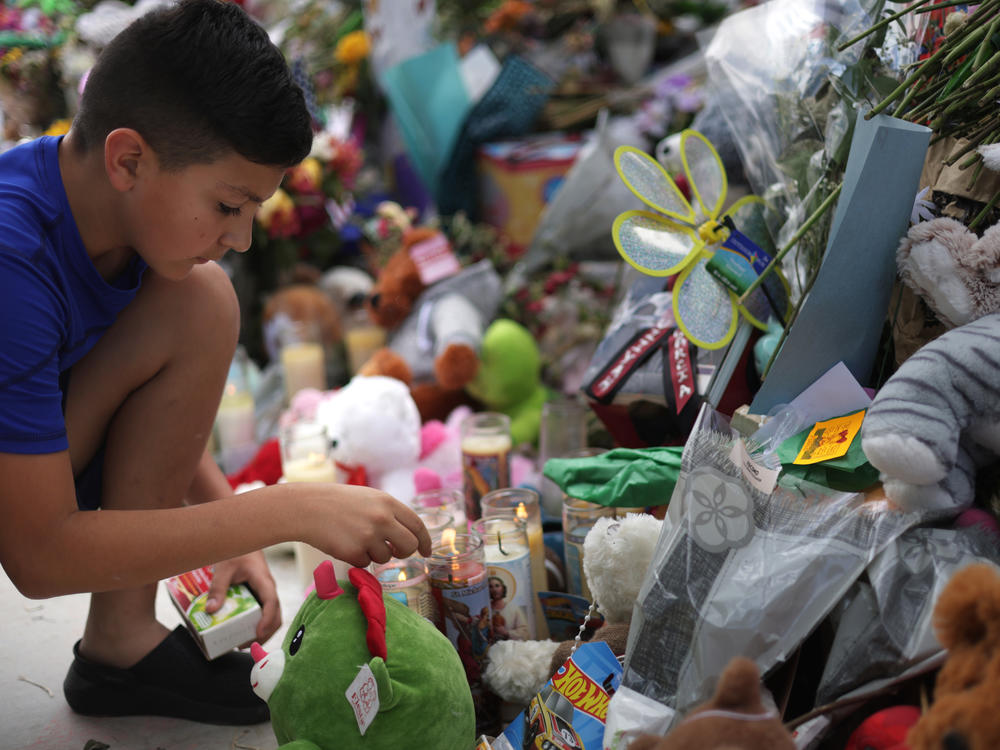 A child lights candles at a memorial for the victims of a May 24 mass shooting at Robb Elementary School in Uvalde, Texas, that killed 21 people, mostly children.