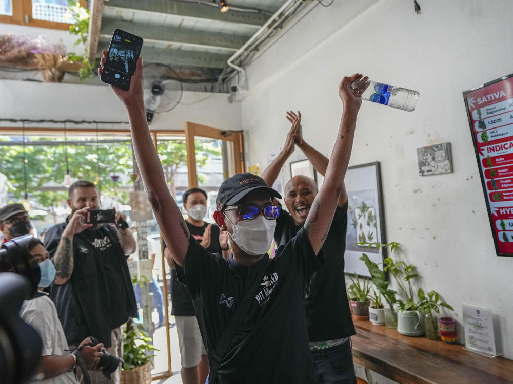 The first customer of the day, Rittipomng Bachkul celebrates after buying legal marijuana at the Highland Cafe in Bangkok, Thailand, Thursday, June 9, 2022.