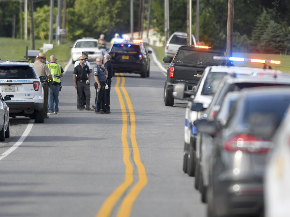 Police work near where a man opened fire at a business, killing three people before the suspect and a state trooper were wounded in a shootout, according to authorities, in Smithsburg, Md., Thursday. The Washington County (Md.) Sheriff's Office said in a news release that three victims were found dead at Columbia Machine Inc. and a fourth victim was critically injured.