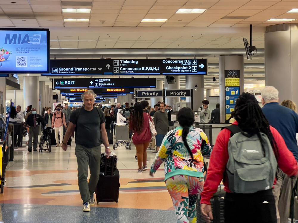 Travelers transit through Miami International Airport in Miami on April 22. Although many Americans are cutting down spending on some stuff, they continue to splurge on travel and eating out.
