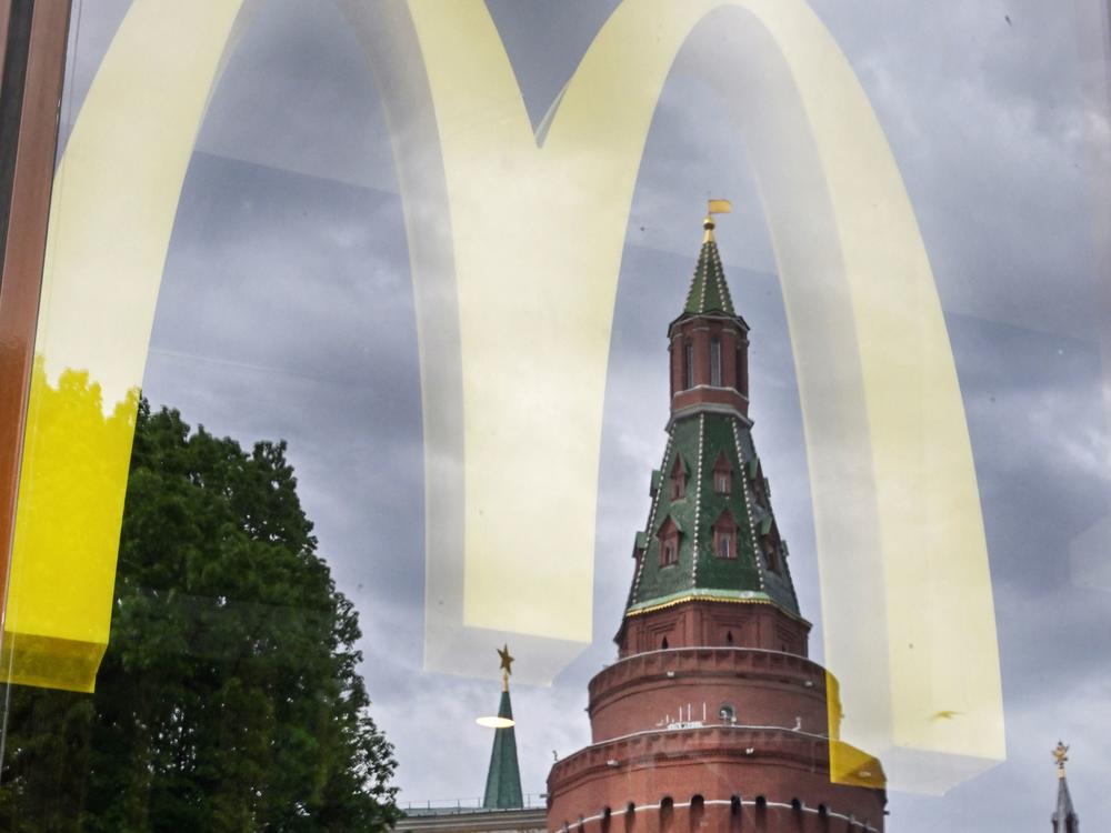 People walk past a window of a McDonald's restaurant as the towers of the Kremlin reflect in it in Moscow on May 26, 2022.