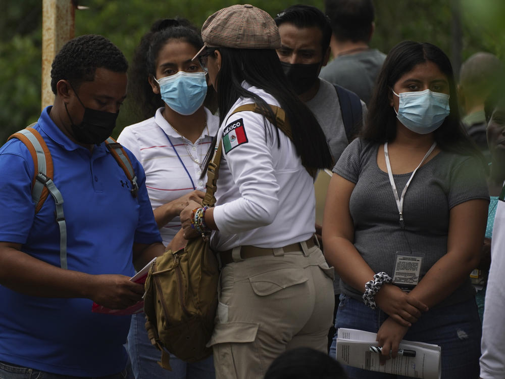 Migrants gathered at the Border Transit Comprehensive Care Center are given documents by an official, center, that allow them to legally travel through Mexico.