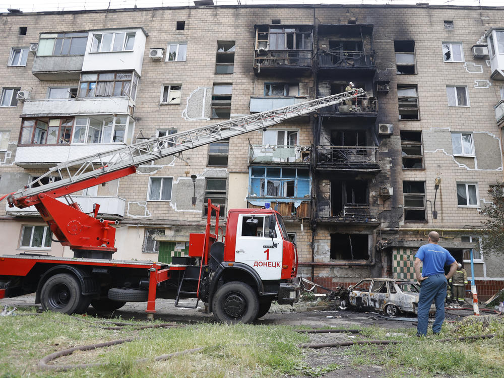 Firefighters work to extinguish an apartment building and cars burning after shelling in Donetsk, eastern Ukraine, on Monday.