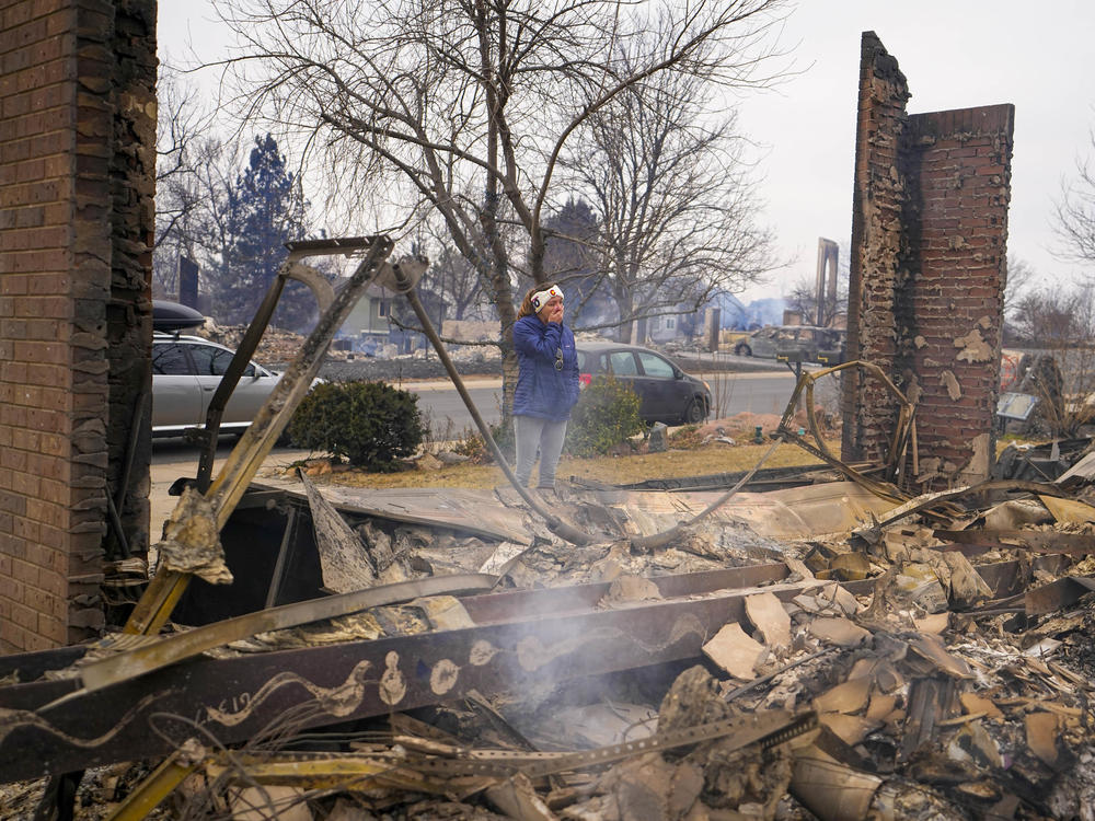 A woman reacts to seeing the remains of her mother's home destroyed by the Marshall Wildfire in Louisville, Colo., in 2021. A new survey finds that most Americans say they have experienced extreme weather in the last five years.