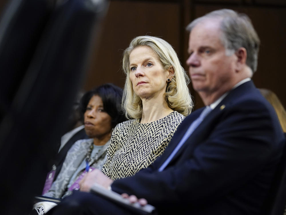 White House Counsel Dana Remus, center, is seated next to former Sen. Doug Jones, D-Ala., right, as they listen during a confirmation hearing for Supreme Court nominee Ketanji Brown Jackson before the Senate Judiciary Committee on Capitol Hill in Washington, Tuesday, March 22, 2022.