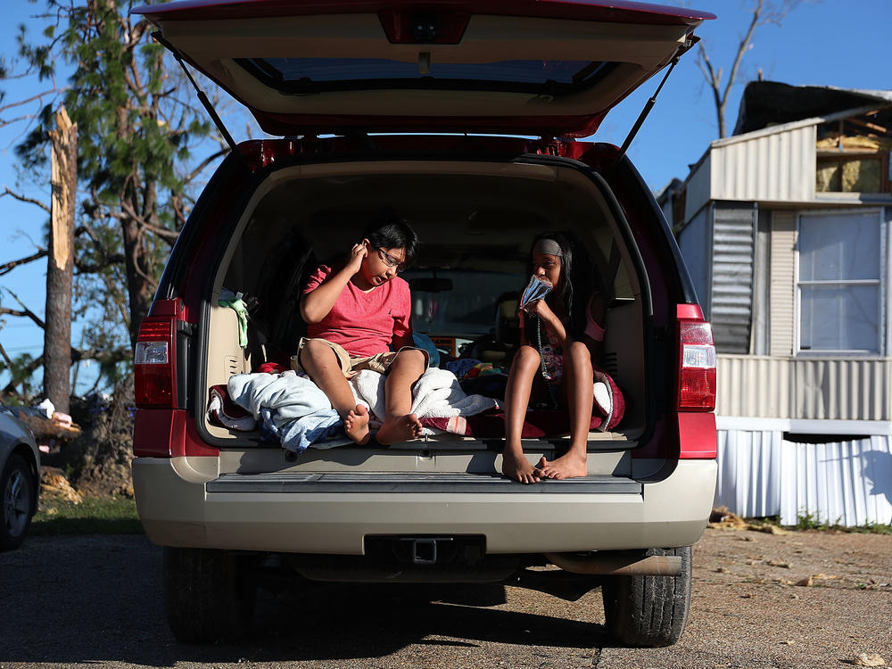 Carlos and Jessica Deviana sit in the back of their father's SUV, which they were using as a bedroom after Hurricane Michael destroyed their home in Panama City, Fla., in October 2018.