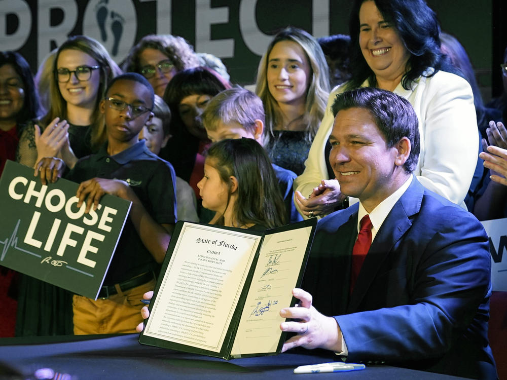 Florida Gov. Ron DeSantis holds up a 15-week abortion ban law after signing it on April 14, in Kissimmee, Fla. A synagogue claims in a lawsuit that the law violates religious freedom rights of Jews in addition to the state constitution's privacy protections.