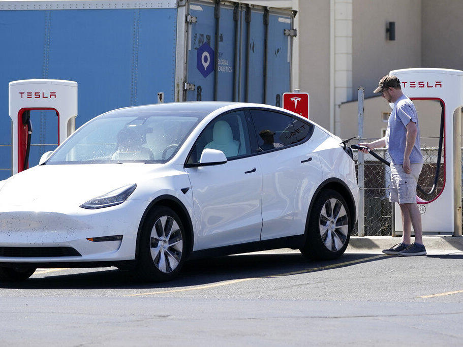 A Tesla owner charges his vehicle in April 2021 at a charging station in Topeka, Kan.. Tesla reported 273 crashes involving partially automated driving systems, according to statistics released by U.S. safety regulators on Wednesday.