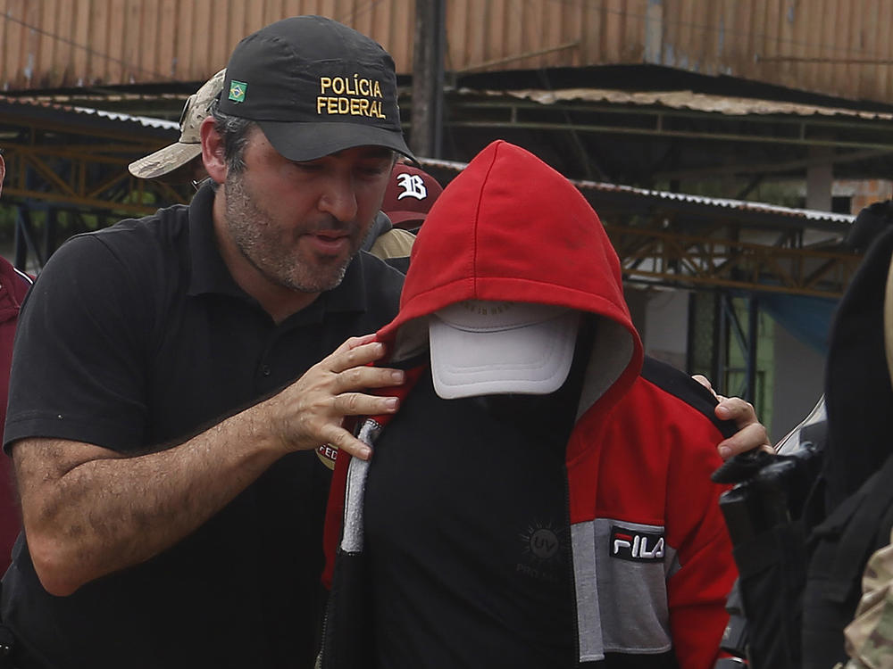 A police officer escorts a suspect in the area where Indigenous expert Bruno Pereira and freelance British journalist Dom Phillips disappeared, in Amazonas state, Brazil, June 15, 2022.