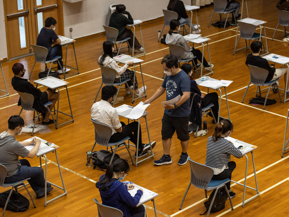 An invigilator distributes papers to students taking the Hong Kong Diploma of Secondary Education exams on April 22, 2022 in Hong Kong.