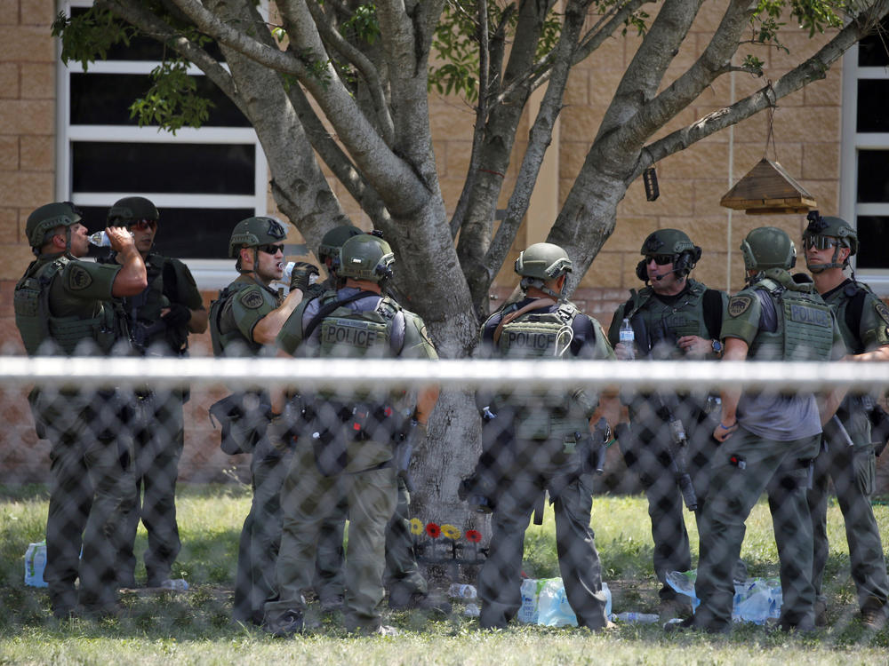 Law enforcement personnel stand outside Robb Elementary School following a shooting on May 24 in Uvalde, Texas. When the gunman arrived at the school, he hopped its fence and easily entered through an unlocked back door, police said.