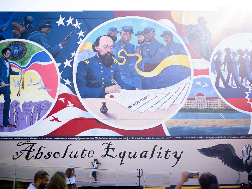 People take pictures next to a mural during a Juneteenth celebration in Galveston, Texas, on June 19, 2021. Last year, the U.S. designated Juneteenth a federal holiday with President Joe Biden urging Americans 